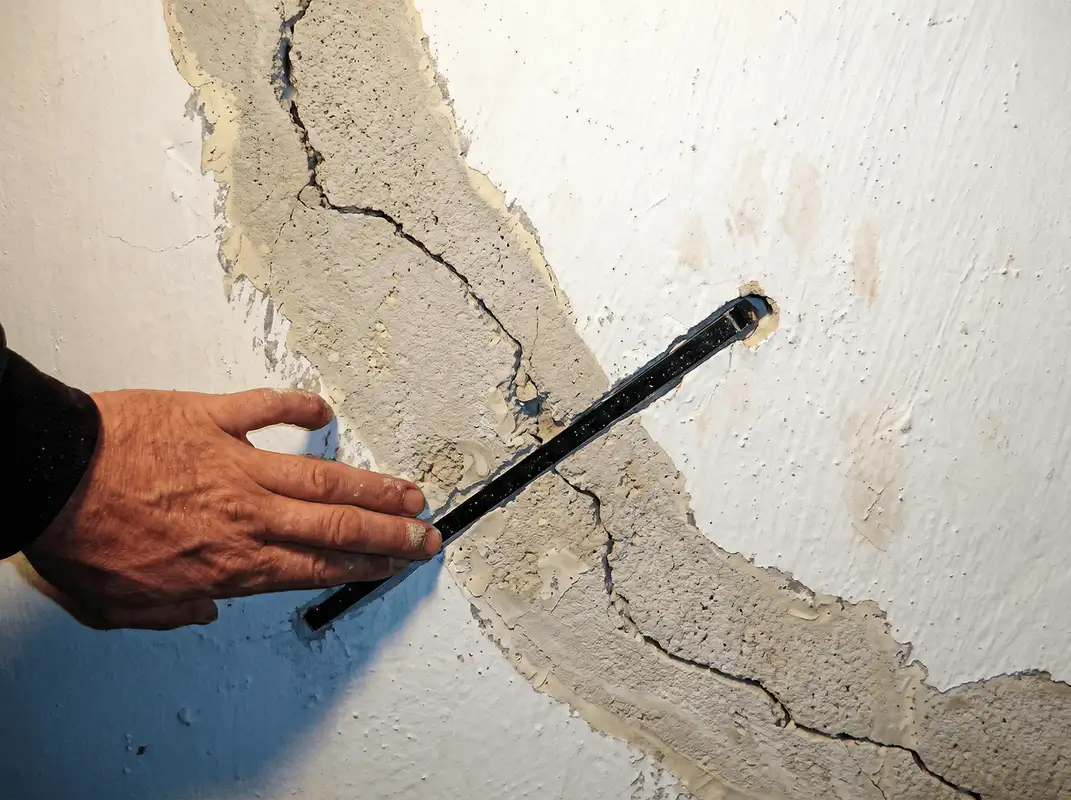 A wall with a large crack is being inspected by a professional in Charleston, SC